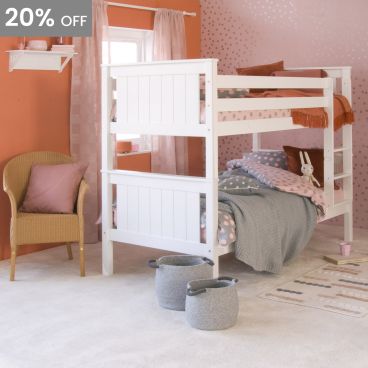 White classic bunk bed in pink and orange themed bohemian girls room, with spotty wallpaper and bedding, wicker chair 