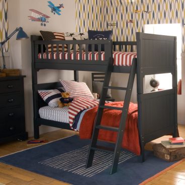 Traditional dark blue boys bunk bed, with red and blue bedding and geometric wallpaper 