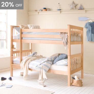 Natural Beech hardwood bunk bed with spindle ends, in front of a beige wall with shelf. Seaside themed bedroom