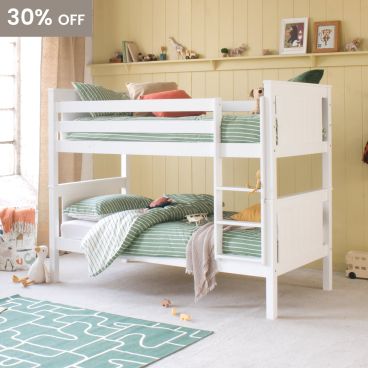 White classic beech detachable bunk bed in pink and orange themed bohemian girls room, with spotty wallpaper and bedding, wicker chair 