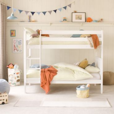 front view of Pip ranch style bunk bed in Pure White, with blue bunting above and orange and blue room accessories