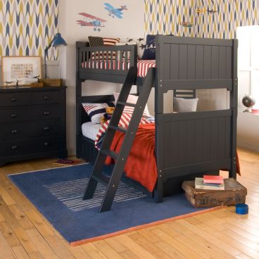 Large dark blue bunk bed with trundle tucked underneath and pitched ladder, Chest of drawers next to it and vintage planes on the wall.