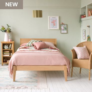 Sleek oak small double bed with pink and green bedding and in a green bedroom with picture rail and high windows 