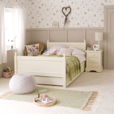 Ivory white traditional solid double bed, 3 drawer bedside table and beanbag and wildflower wallpaper in childs bedroom 