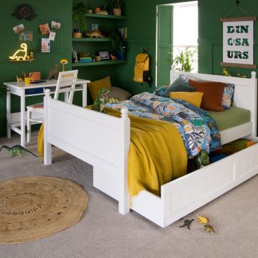 white traditional bed with dinosaur bedding in green bedroom 