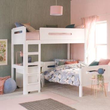 White loft bed with lozenge cut outs, day bed and desk underneath in a pink and green bedroom with blue accessories.