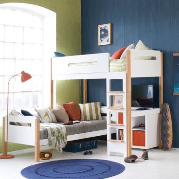 Loft bed with blue and green walls, day bed with cushions, floor standing lamp and natural bed frame. Storage unit underneath with TV screen on to the side