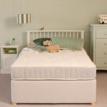 Open Coil small double mattress on bed with green accessories, bedding and dog on top