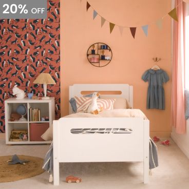 end view of white bed with rounded corners and pill shape cut outs, in bedroom with cat wallpaper
