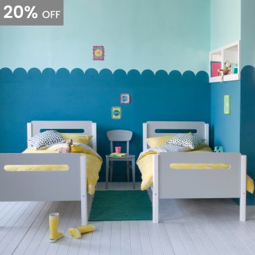 grey and white children's beds with curved corners and pill shape cut outs in the head and foot boards with teal scalloped wall painting 