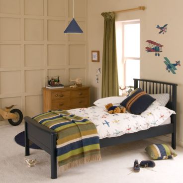 blue single bed with spindles at head board end, chest of drawers in panelled bedroom 