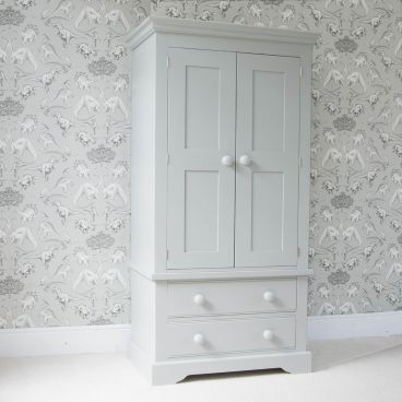 Fargo Farleigh Grey solid wooden wardrobe, with full width hanging space and 2 drawers underneath, standing in front of a grey dinosaur wallpaper.
