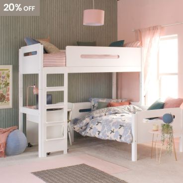 White loft bed with lozenge cut outs, day bed and desk underneath in a pink and green bedroom with blue accessories.