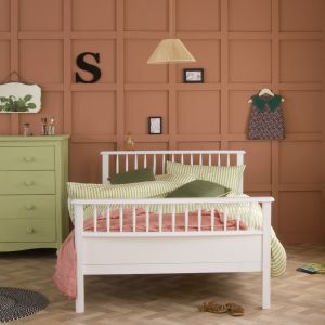 small double bed with terracotta panelling behind and green chest next to it 