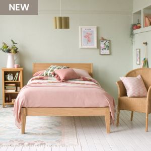 Sleek oak small double bed with pink and green bedding and in a green bedroom with picture rail and high windows 