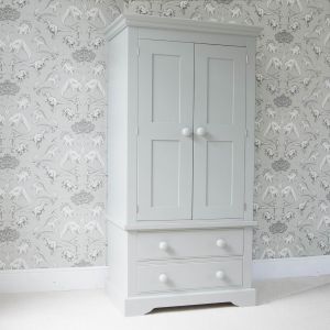 Fargo Farleigh Grey solid wooden wardrobe, with full width hanging space and 2 drawers underneath, standing in front of a grey dinosaur wallpaper.