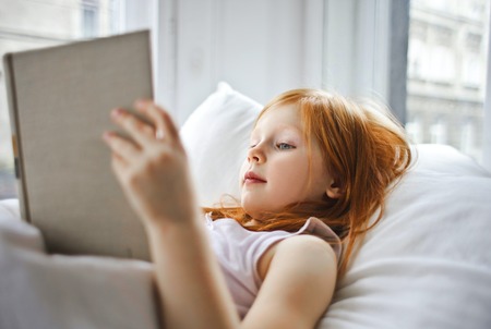 girl reading book in bed