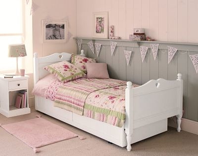 cottage style girls bedroom with white bed, carved heart cut out. Bunting 