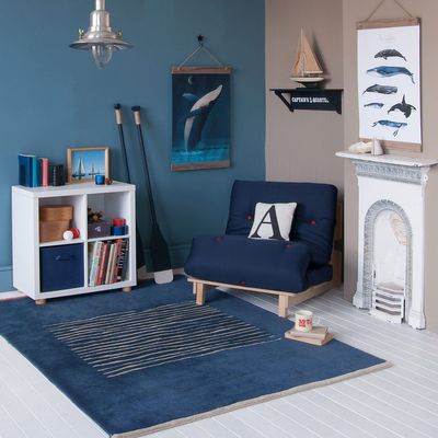 nautical themed corner in kids room, blue futon chair bed, storage, blue and caramel scheme 